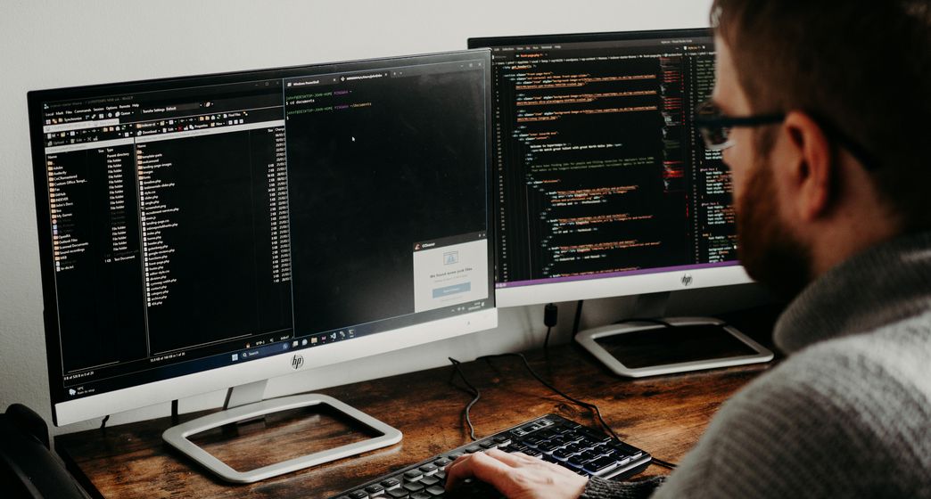 Image of a man programming with two monitors.